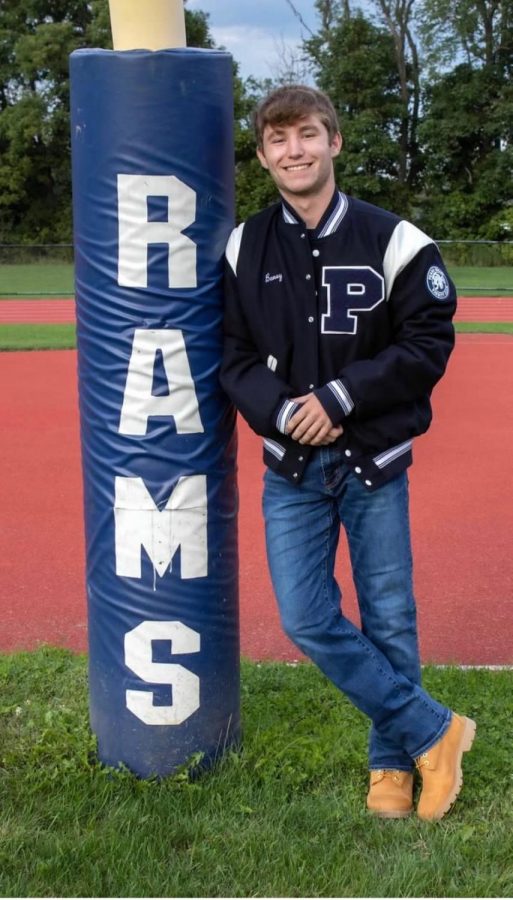 Seth Baney on the football field wearing his varsity jacket
